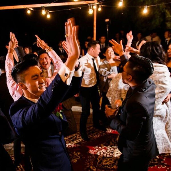 A wedding party dancing under festoon lighting at Belvoir Homestead.