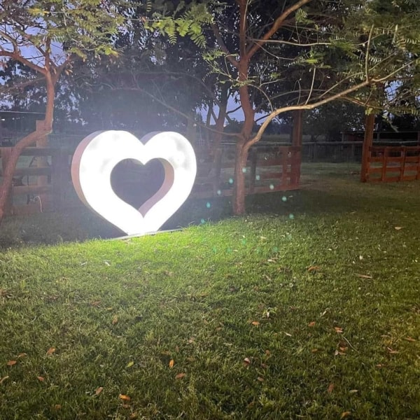 Giant LED light up heart on a lawn at night.