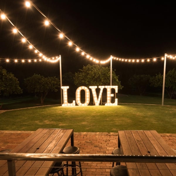 Giant light up love letters under festoon lighting at Core Cider House.