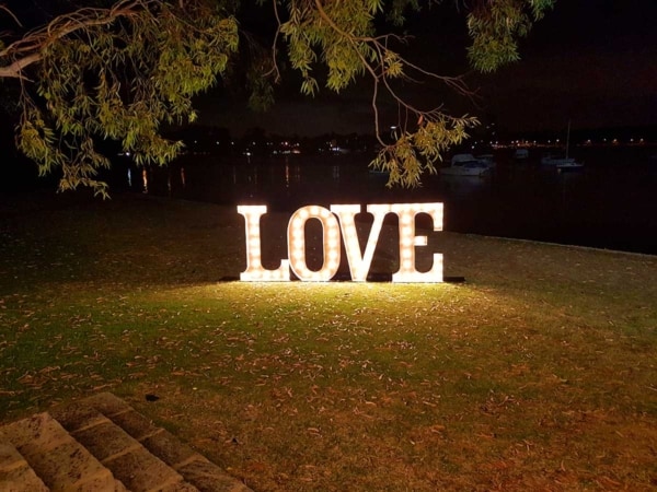 Giant light up love letters under a tree at night.