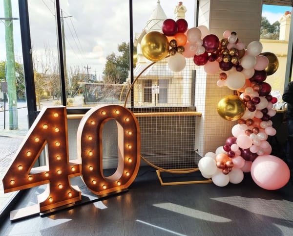 Giant rustic gold 40 number lights and garland of pink and gold balloons.