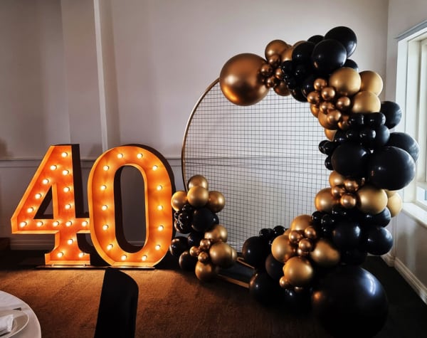Giant number lights and black and gold balloons for a 40th birthday party.