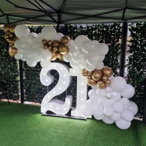 Giant white LED number lights with white and gold balloons at a 21st birthday party.
