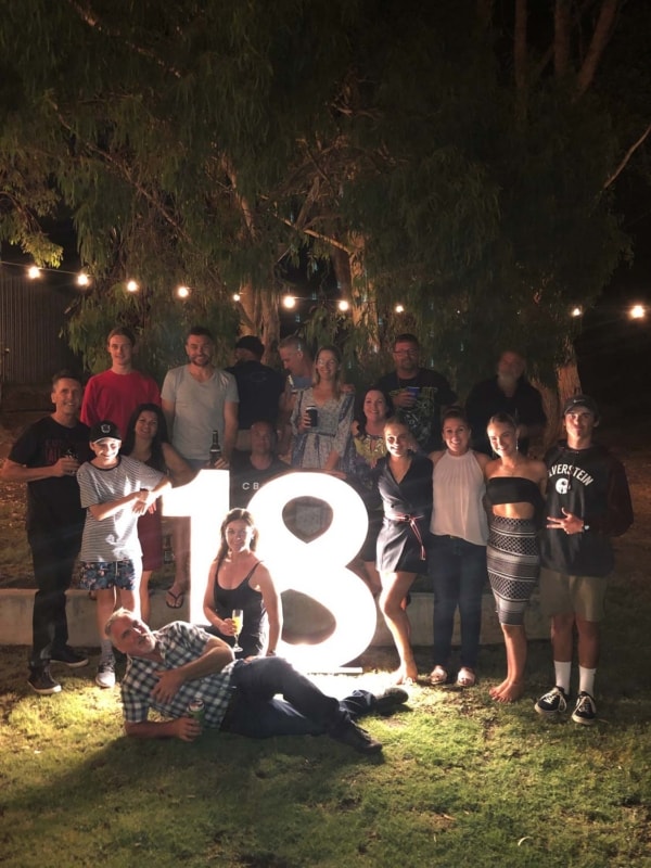 Family gathered around light up numbers at an 18th birthday party.