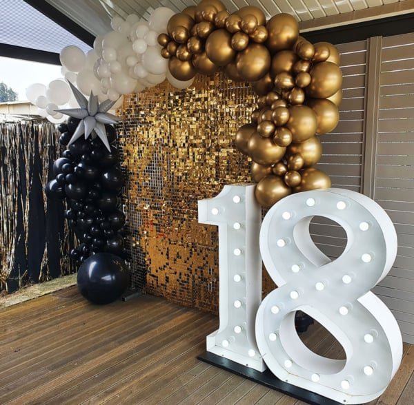 Giant light up numbers with balloons and gold shimmer wall.