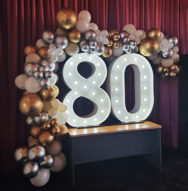 Light up numbers and silver and gold balloons at an 80th birthday.