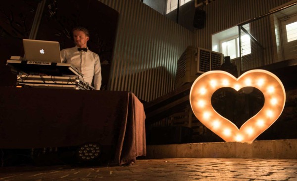 Giant light up rustic gold LED heart with DJ at wedding reception.