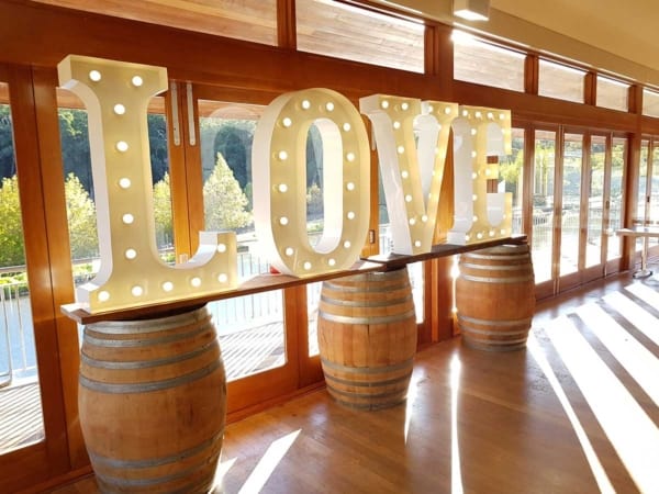 Light up love letters arranged on a row of wine barrels.