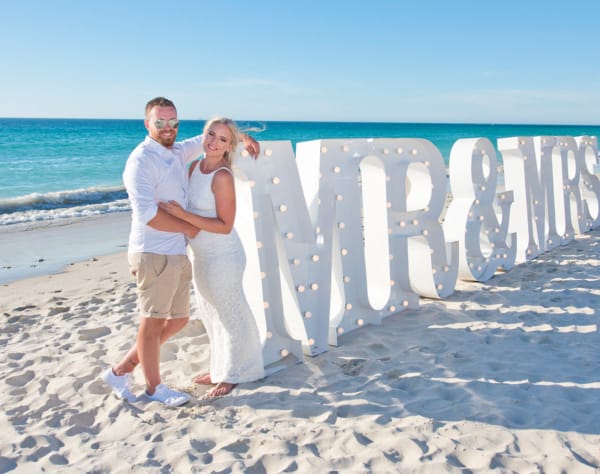 A beach wedding with giant white MR & MRS lit letters.