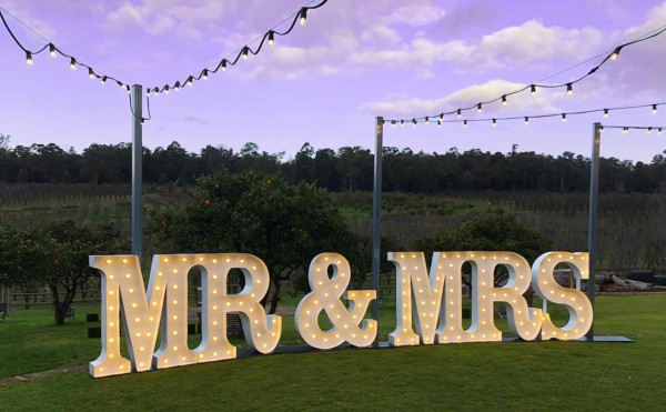 Giant light up MR & MRS LED letters in an orange orchard.