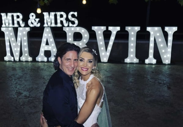 Mr & Mrs Marvin posing in front of giant white LED light up letters at their wedding.