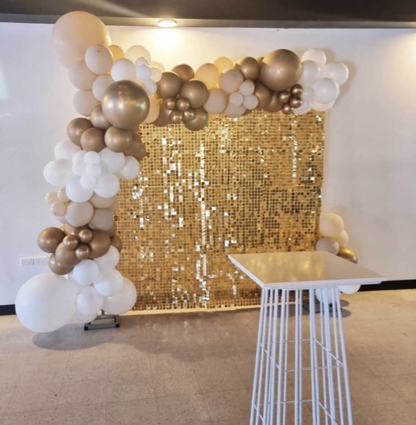 Golden shimmer wall and a white and gold balloon garland.