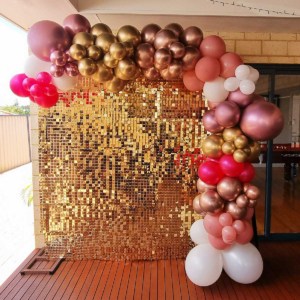 A golden shimmer wall with pink, gold and white balloons.