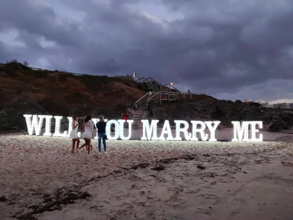 WILL YOU MARRY ME light up letters on a beach in Perth at night.