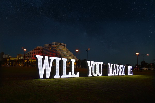 Giant white WILL YOU MARRY ME light up letters at night.